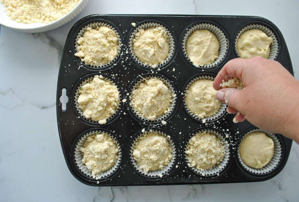 Streusel auf Muffin Teig verteilen für Apfel Muffins mit Streusel