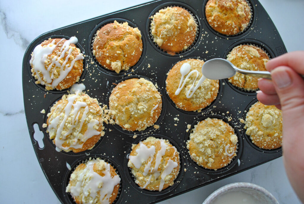 Zuckerguss auf den Apfel Muffins mit Streusel verteilen