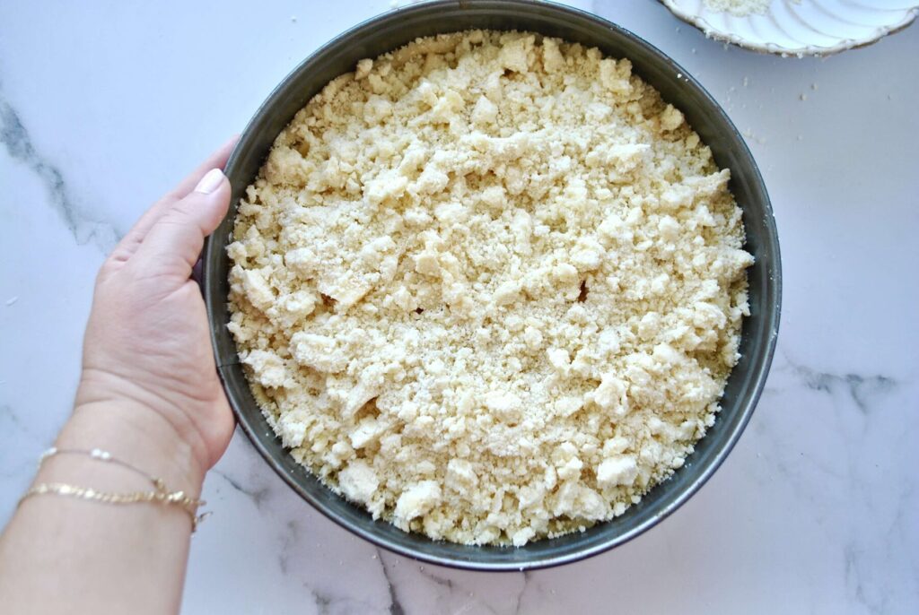 Apfelkuchen mit Pudding und Streusel in den Backofen geben