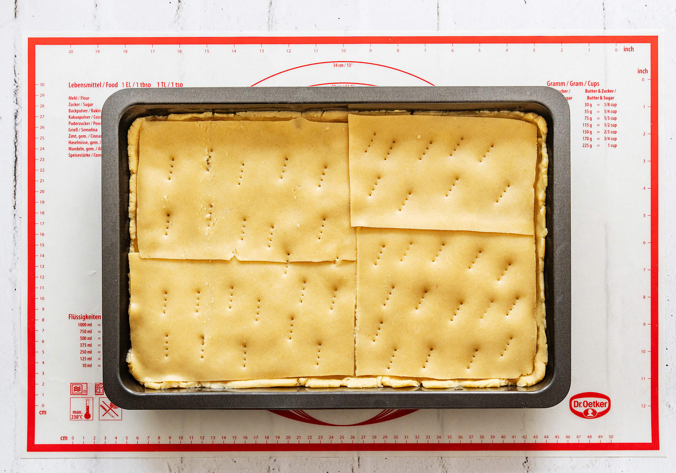 Mürbeteigplatten für die Kuchendecke des Gedeckten Apfelmuskuchens auf dem Kuchen verteilen.