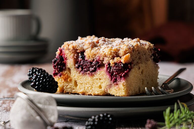 Saftiger Brombeer Streuselkuchen vom Blech in der Nahaufnahme, mit knusprigen Streuseln und deutlich sichtbarer Frangipane-Schicht auf Teller angerichtet.