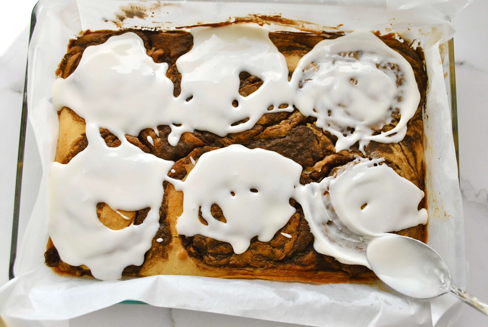 Glasur auf Zimtschneckenkuchen verteilen