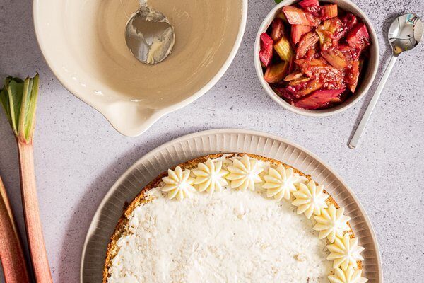 Dekorativer Creme-Rand wird auf den Bienenstich mit Rhabarber dressiert