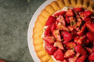 Erdbeerkuchen mit Vanillepudding und weißer Schokolade, dekoriert mit frischen Erdbeeren und Pistazien