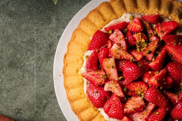Erdbeerkuchen mit Vanillepudding und weißer Schokolade, dekoriert mit frischen Erdbeeren und Pistazien