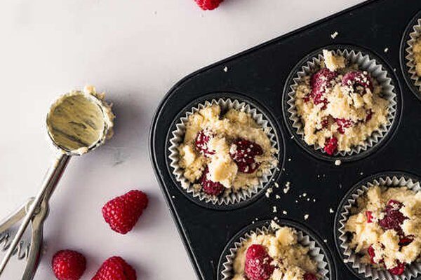 Muffins in der Form mit Himbeeren und Butterstreuseln belegt vor dem Backen