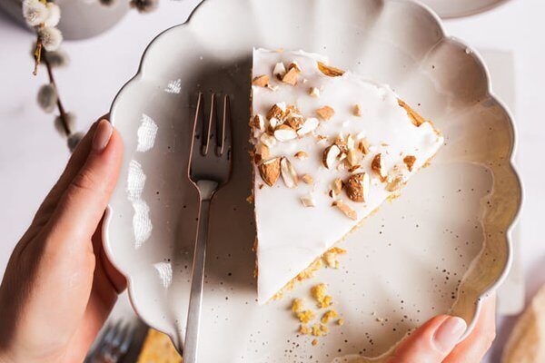 Angeschnittener veganer Karottenkuchen mit Zitronenglasur auf Teller