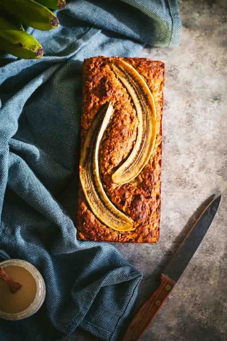 Veganes saftiges Bananenbrot mit Mandeln, aufgeschnitten auf dunklem Untergrund