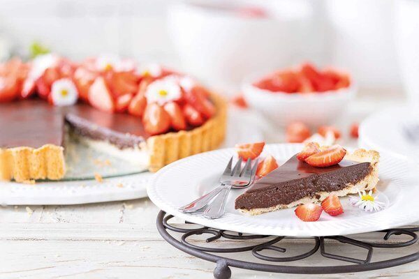 Stück Schokoladenpudding-Tarte mit cremiger Schokofüllung und Erdbeeren auf einem Teller